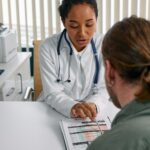 Female doctor discusses health chart with patient during consultation in office setting.
